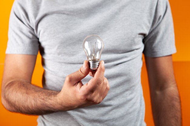 Light bulb in hand on an orange background. Concept idea