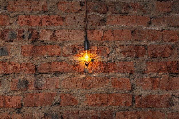 Light bulb hanging on a wire on an old brick wall