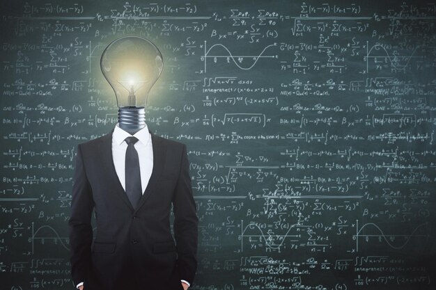 Light bulb headed businessman on chalkboard background with mathematical formulas Science and idea concept