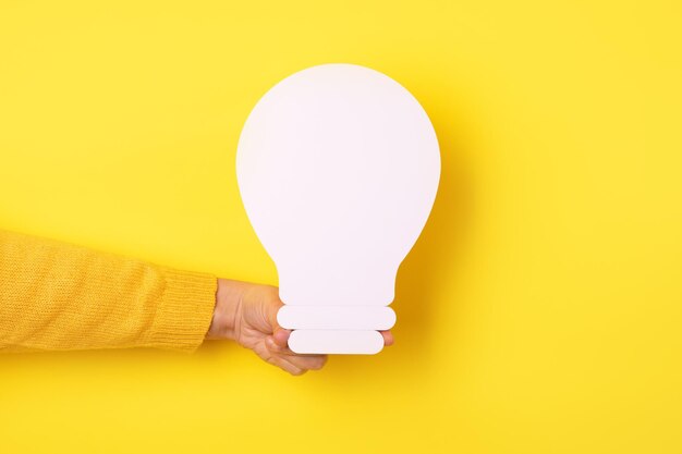 Light bulb icon in hand over yellow background