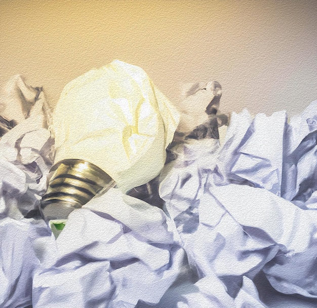 A light bulb is on top of a pile of crumpled paper.