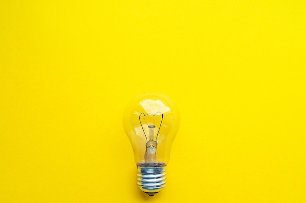 Photo light bulb isolated, yellow background, symbol of idea