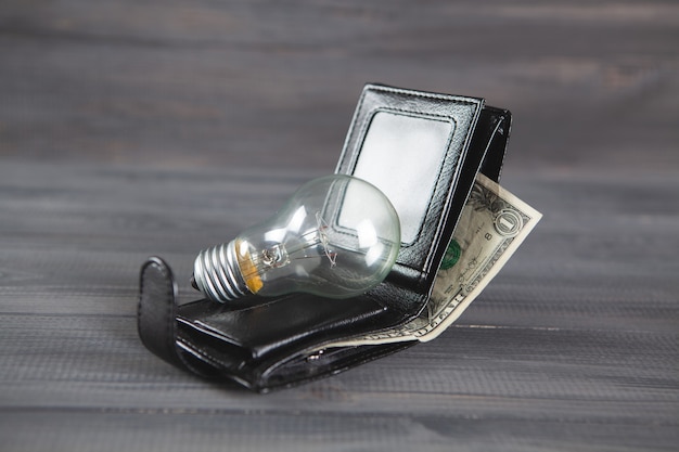 Light bulb on wallet on wooden table