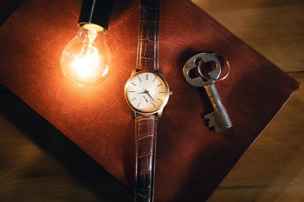 Light bulb and watch with key on the book