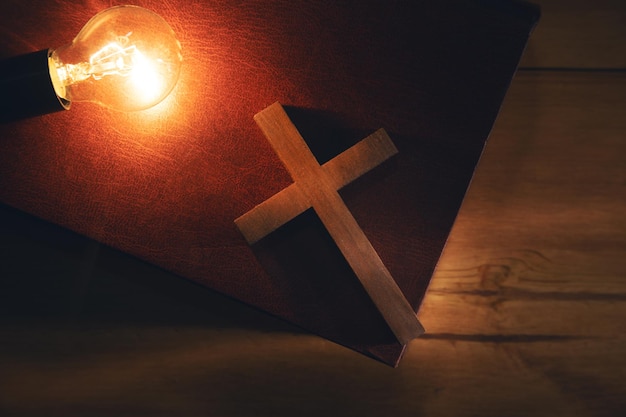 Light bulb with cross on the Bible