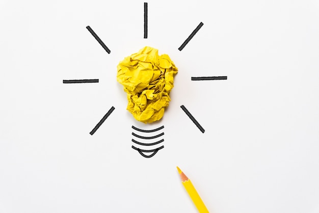 Photo light bulb with crumpled colorful paper and yellow pencil on white background.