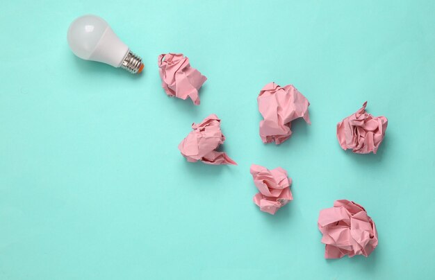 Photo light bulb with crumpled paper balls on blue background creative idea