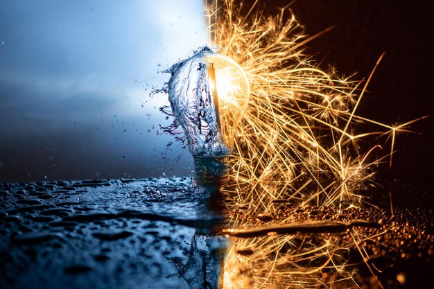 Light bulb with splashing water and sparkling fire on each side.