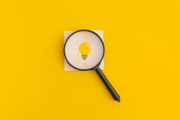 黄色の背景に電球。インスピレーションと創造的なアイデアのコンセプト。上面図。フラットレイ。