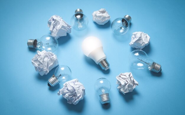 Light bulbs and crumpled papers on the blue surface