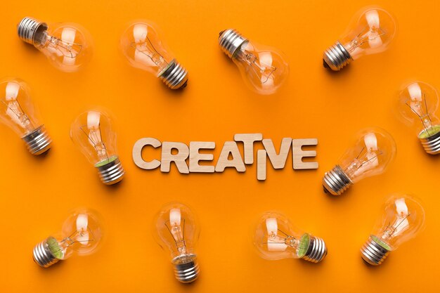 Light bulbs frame and Creative inscription on yellow background, top view. Idea, inspiration and innovation concept