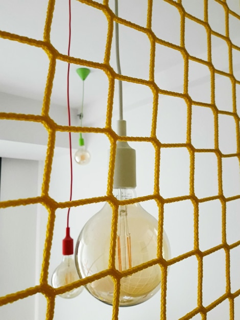 Foto lampadine viste attraverso una recinzione di corde gialle