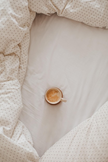 Light cozy bedroom Coffee or tea cup and an open book on the bed Spring still life Breakfast in bed