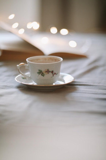 Light cozy bedroom Coffee or tea cup and an open book on the bed Spring still life Breakfast in bed