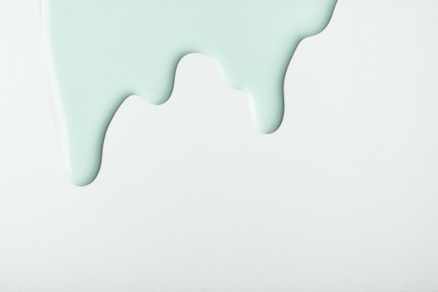 Light cyan liquid drops of paint color flow down on isolated white background Abstract green backdrop