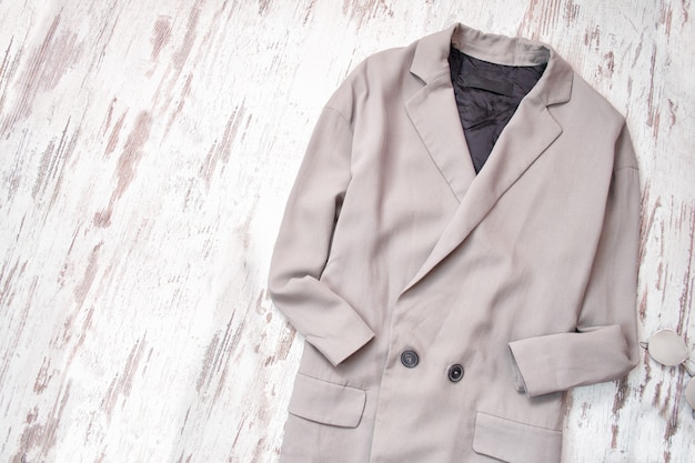 Light gray coat on a wooden background. Fashion concept.