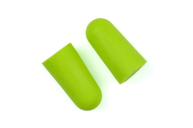 Light green ear plugs isolated on a white backgroundCloseupSoft foam earplug