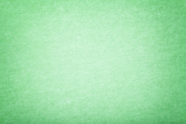 Light green matt suede fabric background. Velvet texture of felt.