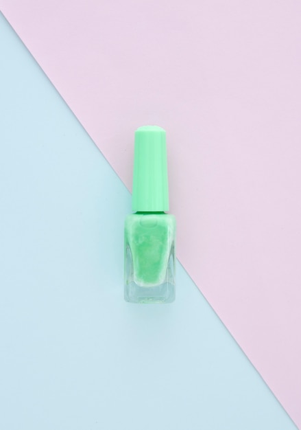 Photo light green nail polish on blank paper with blue color, space for design, beauty concept.