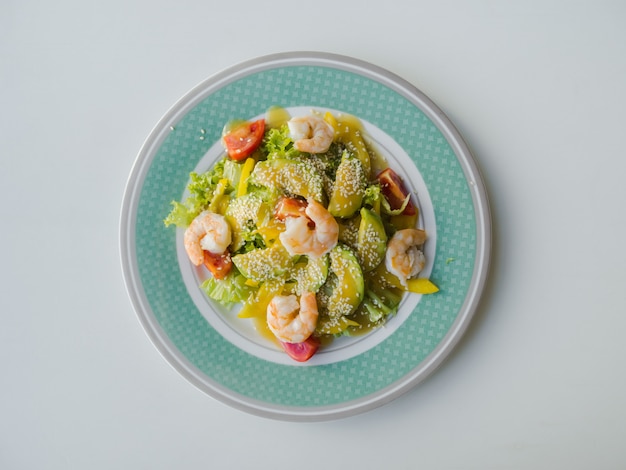 Light green salad with shrimp and avocado on a plate.