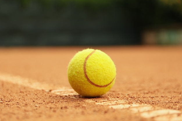 Light green tennis ball on clay court