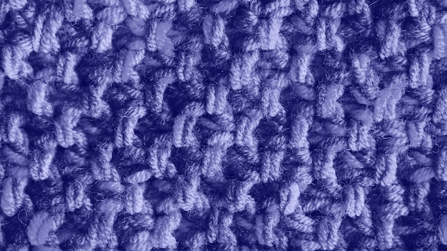 トレンディなバイオレットカラーで着色された軽い手作りのかぎ針編みまたは編み物のテキスタイルファブリックのテクスチャ。マクロの背景を閉じます。