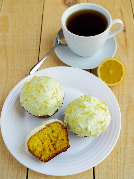 Легкие кексы кексов лимона на деревянных фоне и чашка чая.