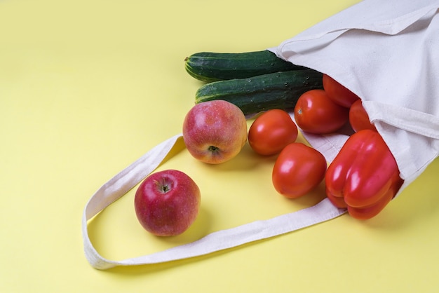 新鮮な野菜や果物が入った軽いリネンのエコバッグ。