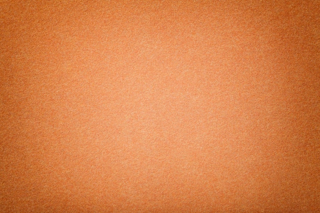 Primo piano del tessuto scamosciato opaco arancione chiaro. texture vellutata di feltro.