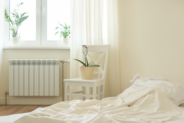 Light pastel bedroom interior, bed, white chair, window, light curtains.