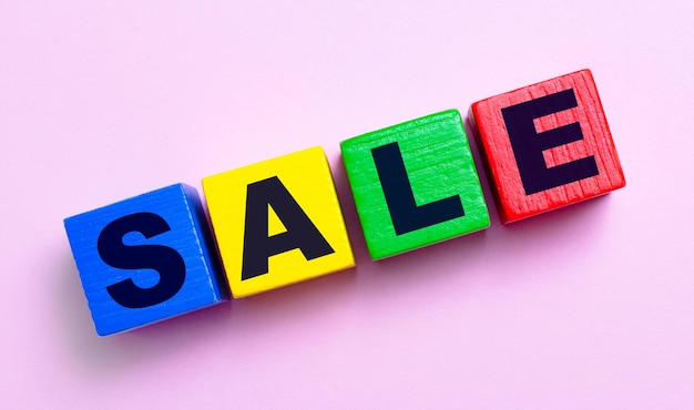 On a light pink background, multi-colored wooden cubes with the text SALE