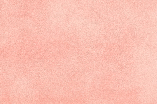 Light pink matte background of suede fabric, closeup. Velvet texture of  rose felt textile, macro.