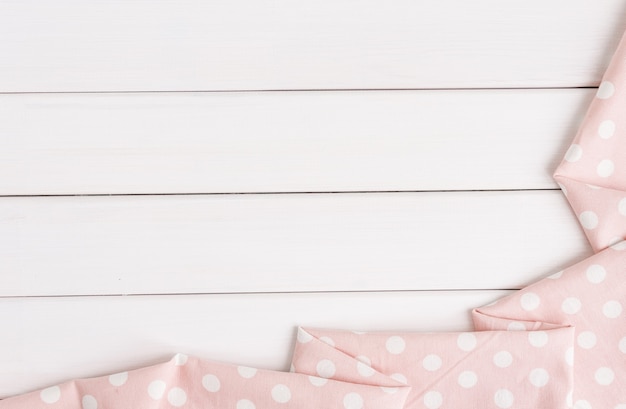 Light pink polka dots folded tablecloth over bleached wooden table. Top view image. Copyspace 