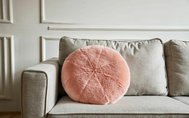 Light pink round cushion with plush texture on a sofa