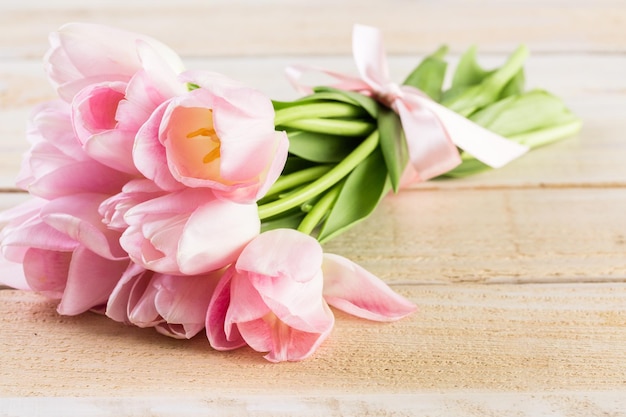 Light pink tulips on a wood background.