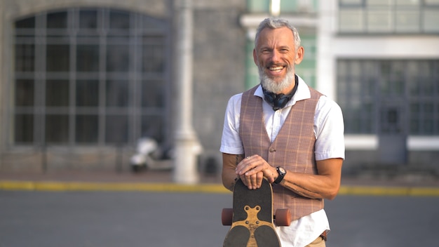 Light-skinned attractive bearded man having fun holding a longboard