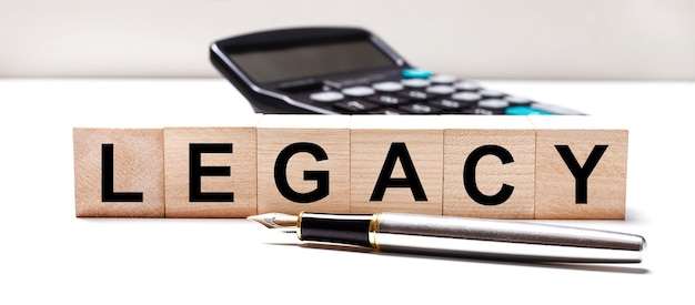 The light table has a black calculator a fountain pen and wooden cubes with the text LEGACY Business concept