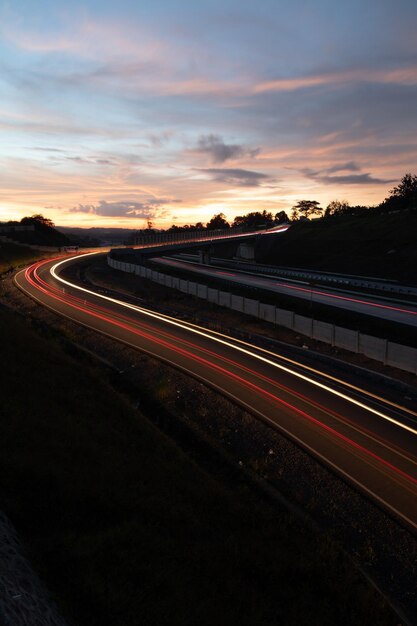 Light trails on road against sky at sunset