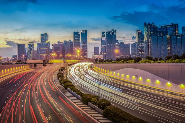 Light trails on road amidst buildings against sky at night