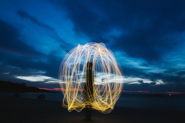 Light trails in sea against sky at night