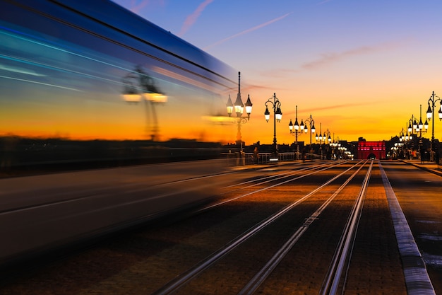 Light trails of tramway on Pont de Pierre stone bridge over garonne river in Bordeaux