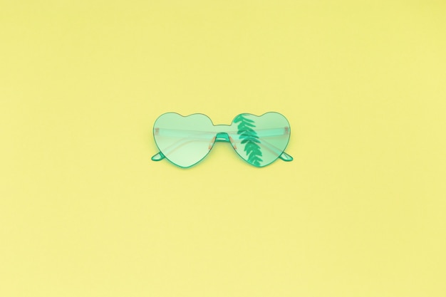 Light turquoise modern sunglasses with shadow of palm leaves.