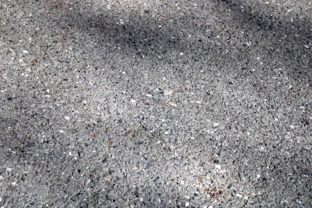 A light wall of stone chips with a shadow falling on it The texture of the stone Universal natural background