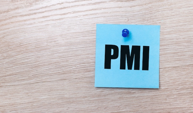 On a light wooden background - a light blue square sticker with the text PMI Project Management Institute