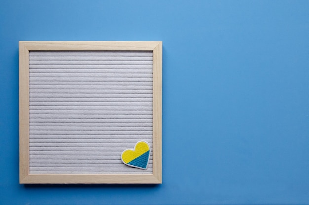 Light wooden letter board and embroidered heart on a blue horizontal background