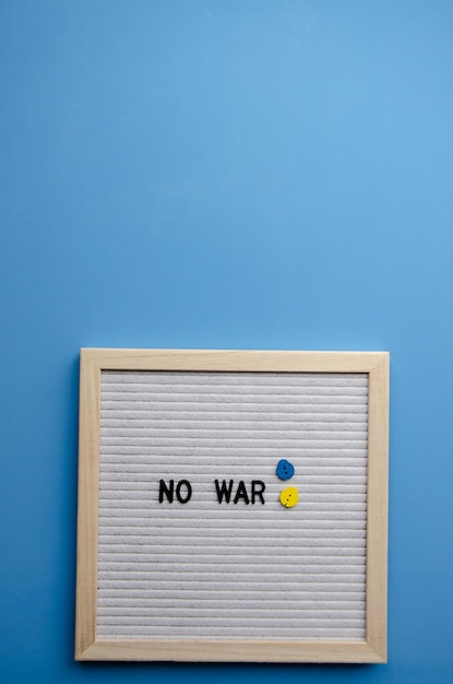 Light wooden letter board and slogan no war on blue background