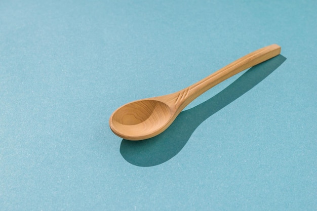 Light wooden spoon on a blue background in hard light