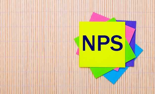 On a light wooden surface, bright multicolored stickers with the text NPS Net Promoter Score