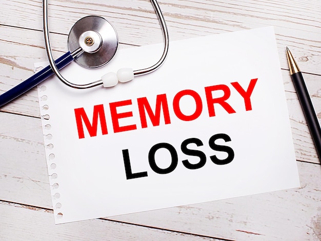 明るい木製のテーブルには、聴診器、ペン、および「MEMORYLOSSMedicalconcept」というテキストが書かれた1枚の紙があります。