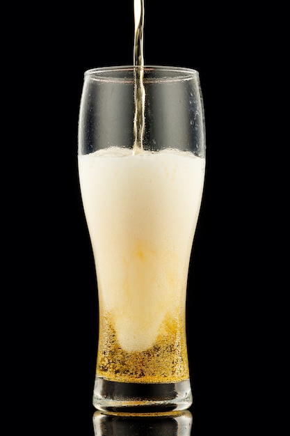 Photo light yellow beer with foam in a glass black background